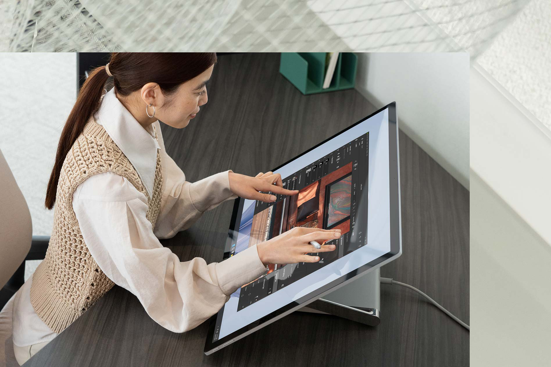 A person uses two hands to complete tasks while touching a Surface Studio 2+ in the office.