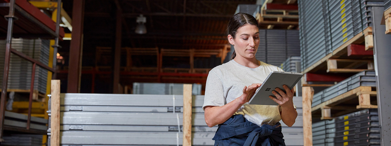 Žena ve výrobním prostředí drží zařízení Surface Pro