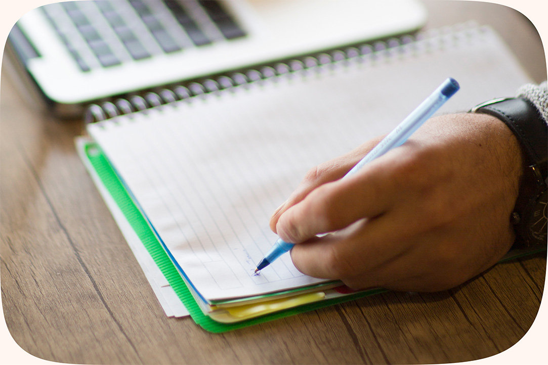 A student’s hand holding a pencil, taking notes on a notebook