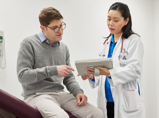 Lekarz używający urządzenia Surface Pro, aby pokazać pacjentowi jego plan opieki zdrowotnej