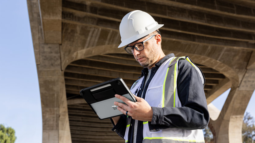 A person in a construction hat and vest using a Surface device