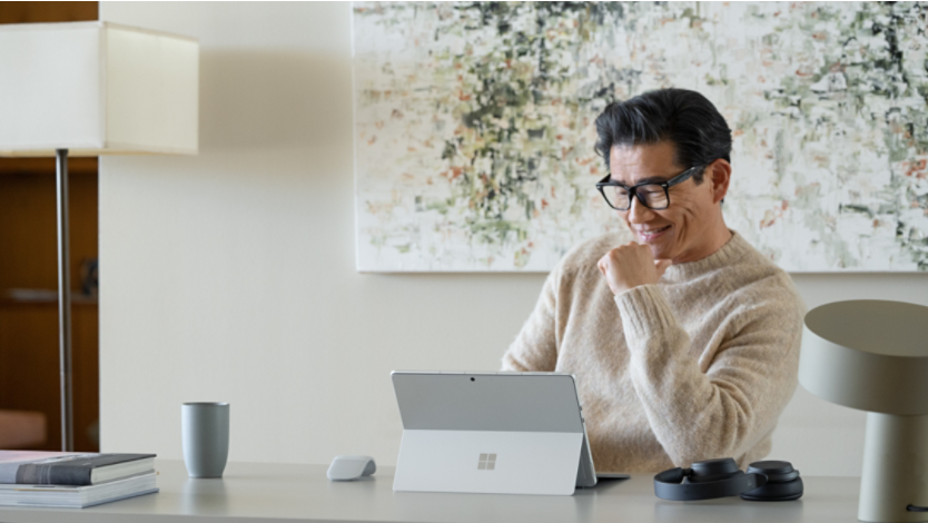 man in cream long sleeve shirt using Surface at home