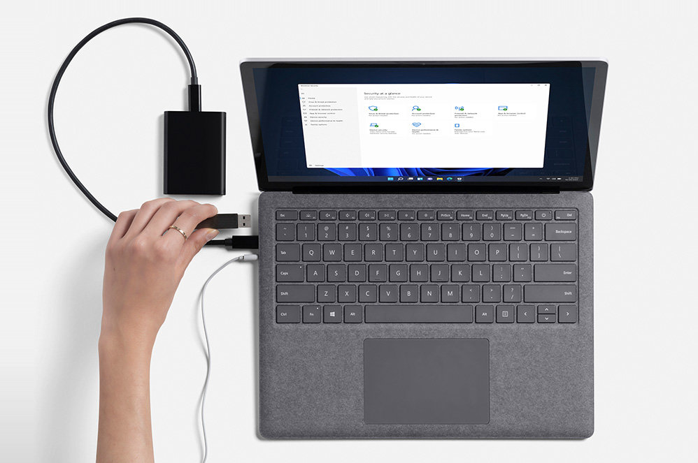 A person’s hand is observed plugging in an external hard drive on Surface Laptop 4