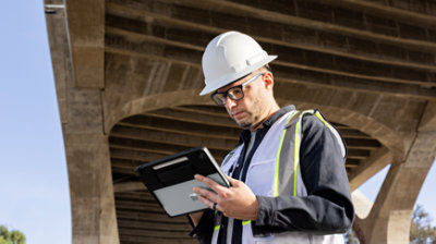 พนักงานส่วนหน้ากำลังถืออุปกรณ์อยู่ใต้สะพาน