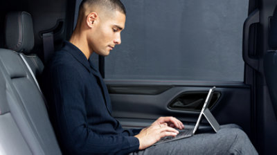 คนกำลังนั่งอยู่ในรถและทำงานด้วยอุปกรณ์