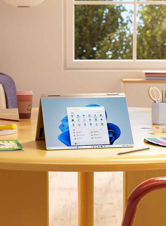 펼쳐진 상태로 탁자에 놓여 있는 Windows 11 디바이스