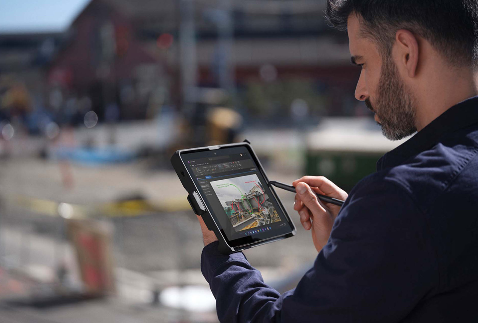 A person on-the-go at a job site uses their Surface Pen to navigate Surface Go 3
