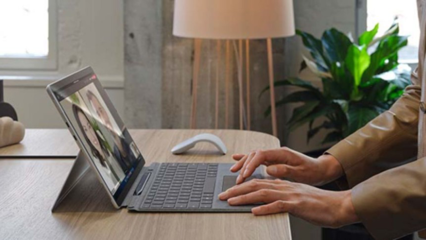 Person im Büro tippt auf einem Surface Pro X im Laptopmodus