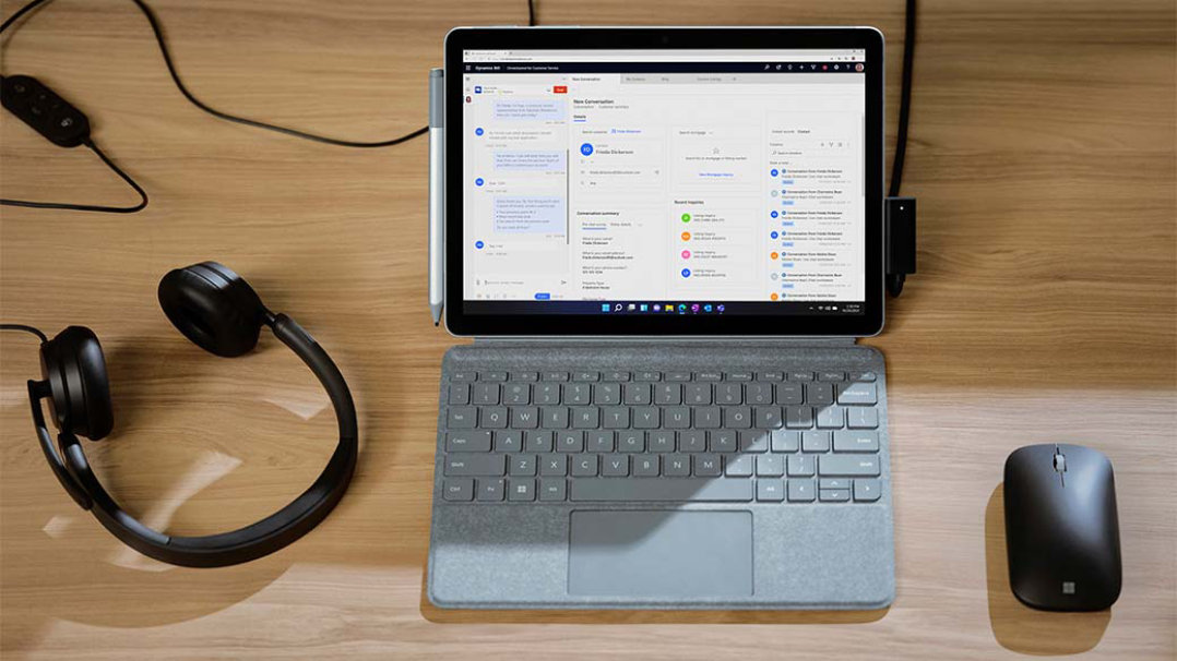 Microsoft モダン USB ヘッドセットおよび Surface モバイル マウスと一緒にデスクの上に置かれた Surface Go 3