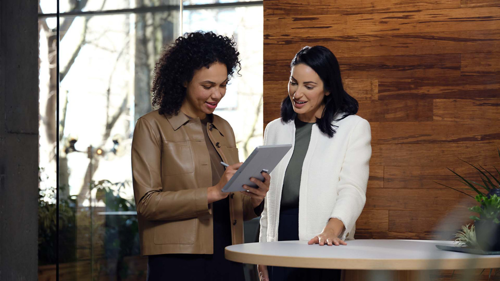 Doi colegi colaborează utilizând un dispozitiv Surface Go 3 la birou