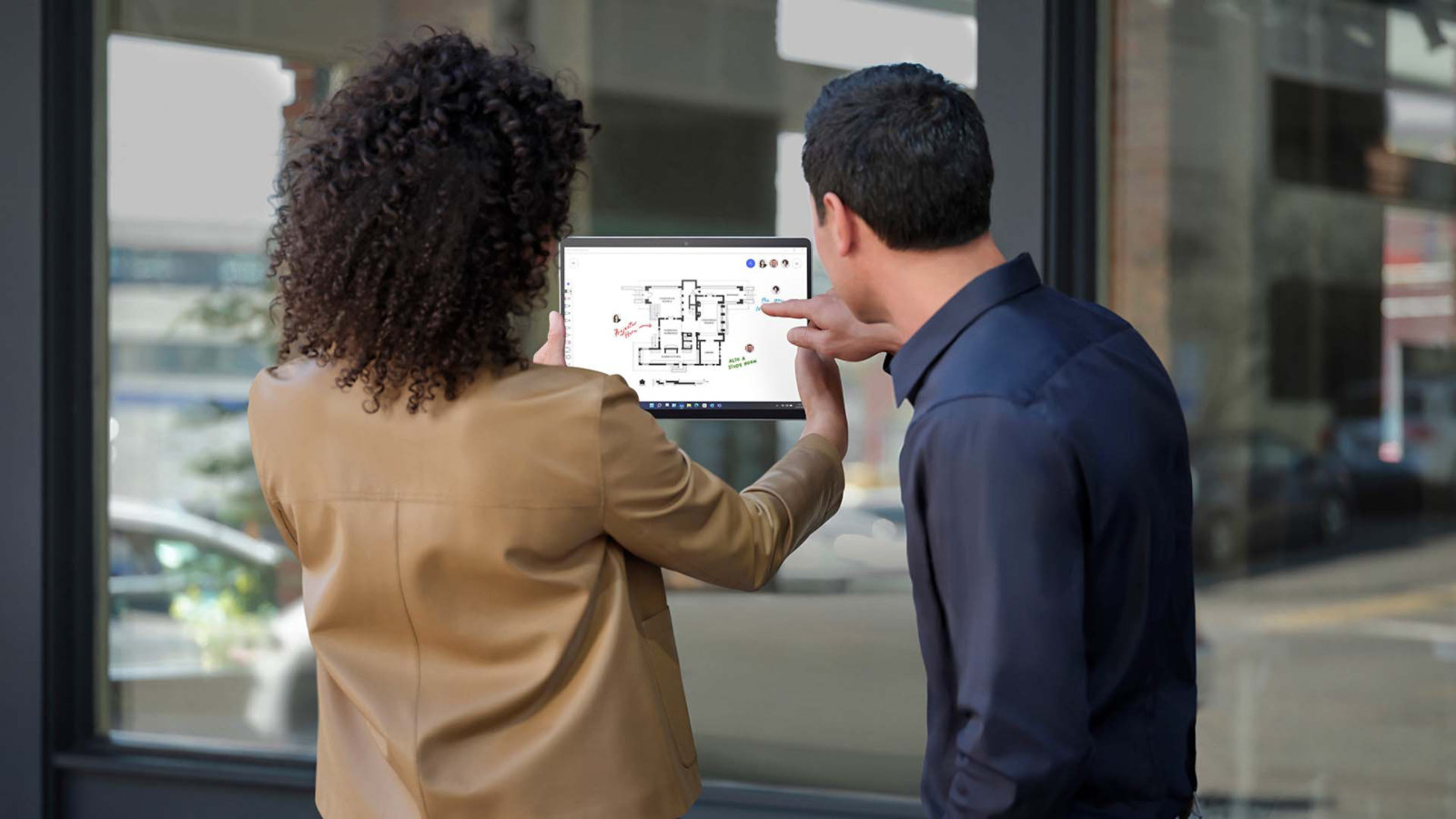 兩個人站在店面外，使用採用平板電腦模式的 Surface Pro X 拍照