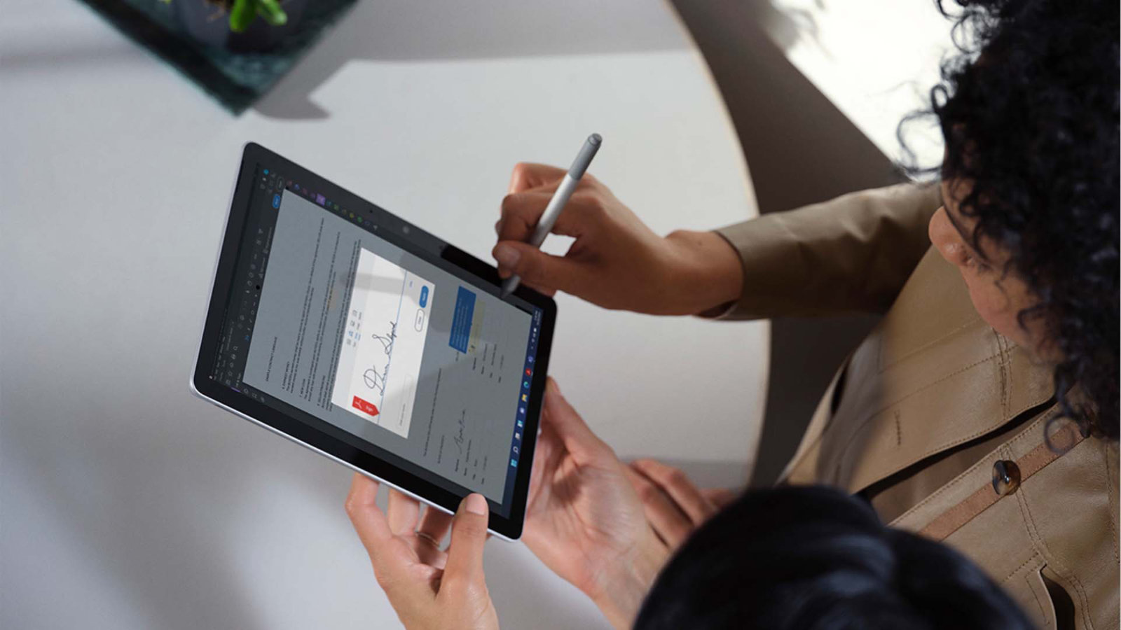 O imagine de sus în jos cu doi colegi care revizuiesc un document împreună pe un dispozitiv Surface Go 3