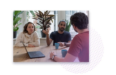 Three people having a meeting with coffees and a laptop