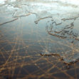 Digital world map with orange lines forming a web of connections across continents, symbolizing global networks or data flow.