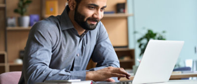 A person looking at a Laptop and smiling.