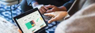 Mains tenant une tablette affichant des graphiques et diagrammes de données dans Dynamics 365