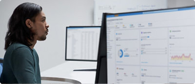 Un hombre sentado delante de dos monitores mirando los datos.