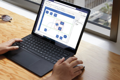 Hands using a laptop that is displaying a Visio file in Microsoft Teams. The Comments pane is open to show a comment and reply.