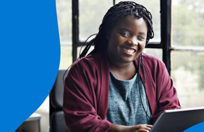 A person with one eye closed smiling and using a laptop.