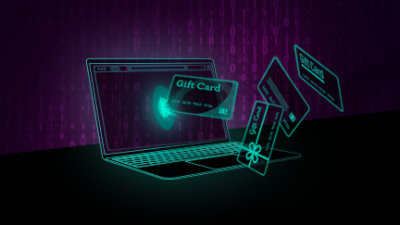 A laptop with gift cards and credit cards flying out of it