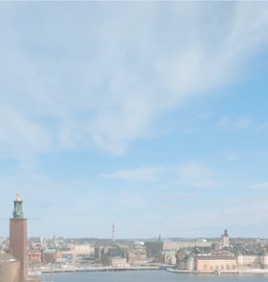 En panoramisk udsigt over Stockholm by med rådhustårnet og spredte spir under en klar himmel.