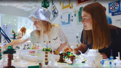 Duas pessoas juntas envolvidas na montagem de uma estrutura de lego colorida.