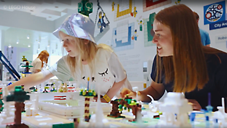 Два человека вместе собирают красочную конструкцию из блоков LEGO.
