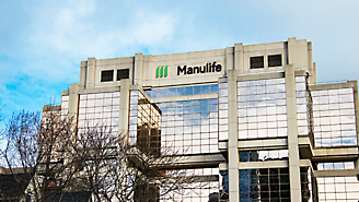 Modern kontorsbyggnad med Manulife-logotyp på fasaden mot en molnig himmel.