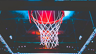 Una canasta de baloncesto con una red, vista desde abajo con un resplandor rojo en el fondo