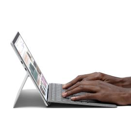 Mãos digitando em um teclado e dispositivo Surface Pro X.