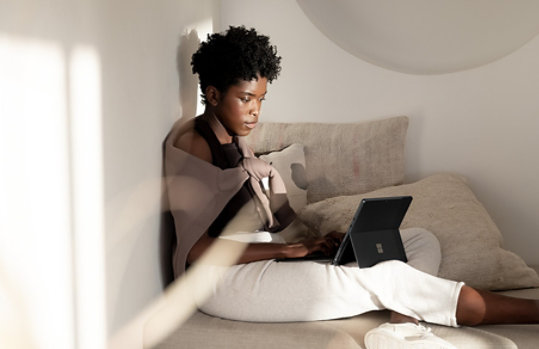 A person relaxing with Surface Pro 8 in kickstand mode.