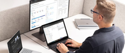 A person sitting at a desk using a laptop with a visible screen.