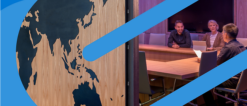 Een houten paneel met een wereldkaartontwerp afgezet tegen een kantoorscène met drie professionals