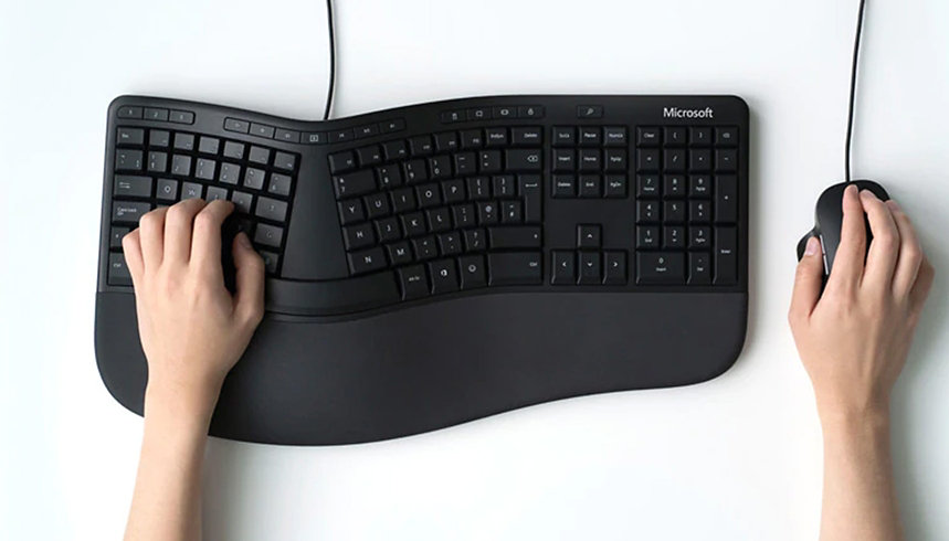 Una persona trabaja en un Microsoft Ergonomic Keyboard con un Microsoft Ergonomic Mouse