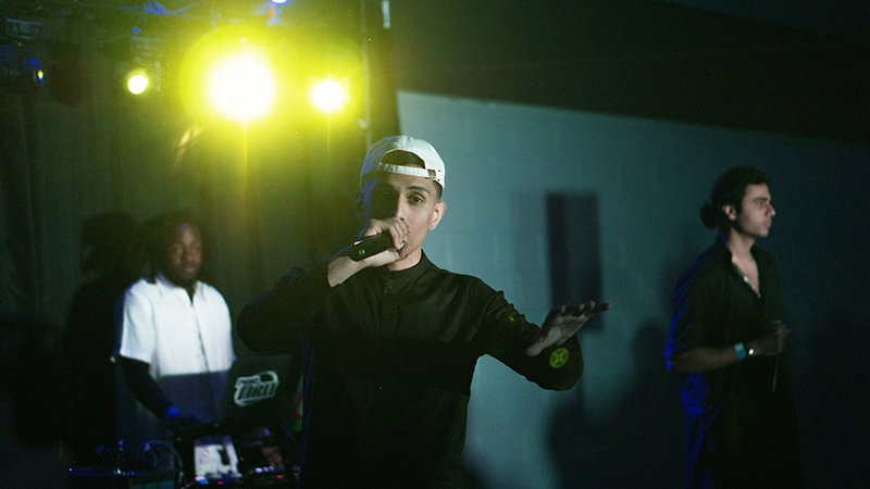 Muhammed Saif, vêtu d’une casquette et d’une tenue sombre, rappe lors d’un spectacle