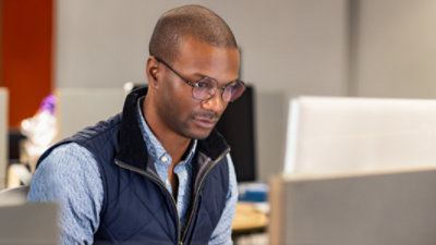 Eine Person in einem Lager, die ein Tablet hält und auf Kartons schaut