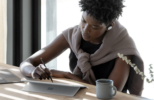 有人坐在桌前，在 Surface Pro 8 上書寫。