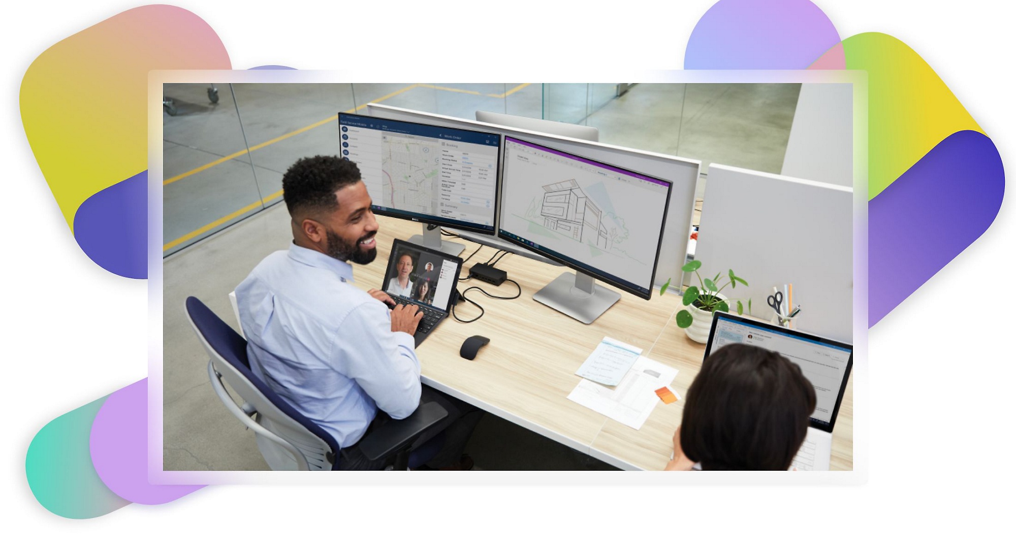 Zwei Personen an einem Schreibtisch, eine davon nimmt an einem Teams-Videoanruf teil und schaut sich Architekturentwürfe und Karten auf zwei Monitoren an