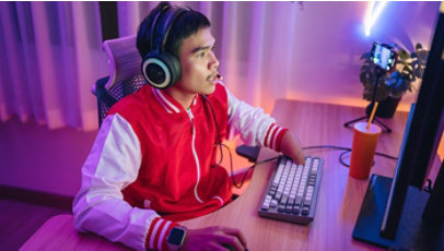 A disabled male gamer is wearing a headset and playing exciting online games in a neon-lit room.