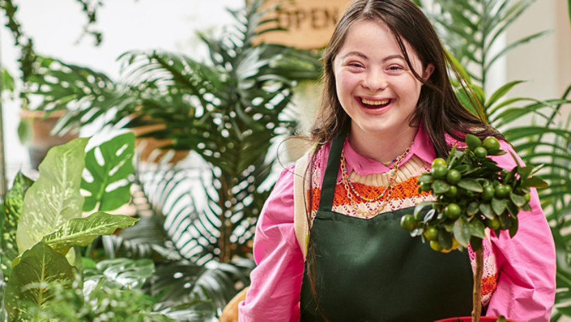 Portrait of young adult female in a flower shop laughing.