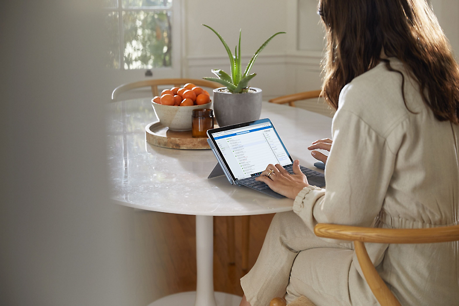 Köögilaua taga istuv inimene kasutab tahvelarvutit, et vaadata talle ülesannete jaotises määratud ülesandeid.