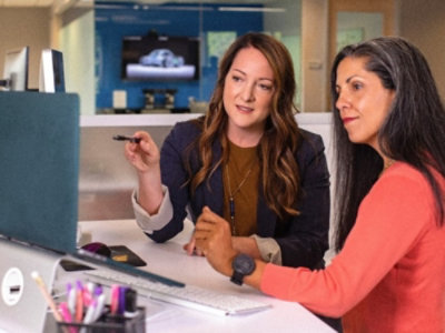 Two women sitting at a desk looking at a computer