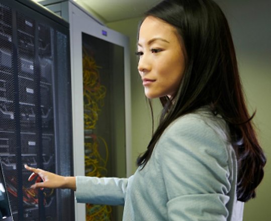 Eine Frau, die den Monitor im Serverraum überprüft