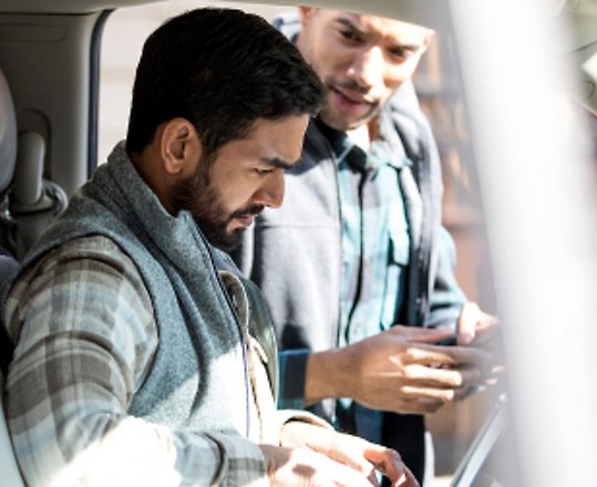 Ein Mann sitzt im Büro und arbeitet mit einer Microsoft Surface Pro und lächelt