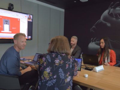 A group of people sitting around a table with laptops