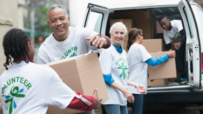 Group of volunteers passing cardboard boxes from delivery van