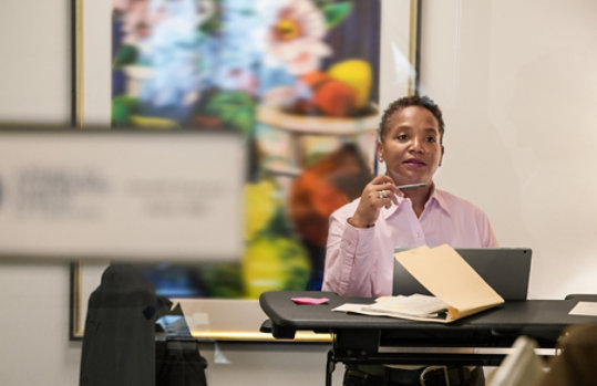 Person in professional clothing sitting in front of a laptop in an office