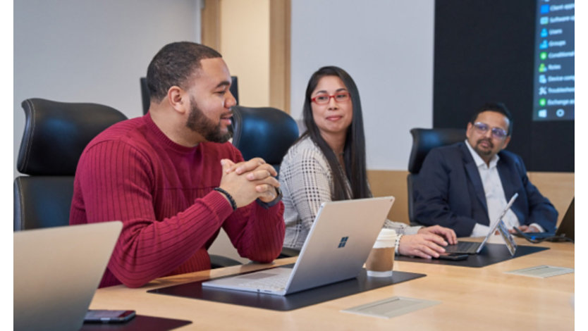 En gruppe mennesker ved et konferencebord med laptops, der ser ud til at have en sund og positiv diskussion eller et møde