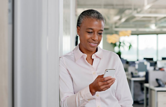 Mujer de negocios enviando un mensaje de texto en la oficina