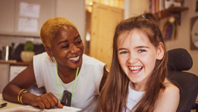 An adult and a child smile inside a room.